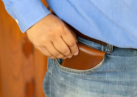 Close-up of a the hand put brown wallet to jeans bag. Stock Photos