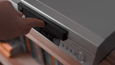 Close up of a hand puting a videotape into video player. Retro vhs cassete. Stock Footage 305183093