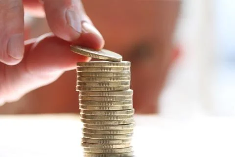 Close-up Of Hand putting a coin to stack of coins. Business Finance and Money Stock Photos