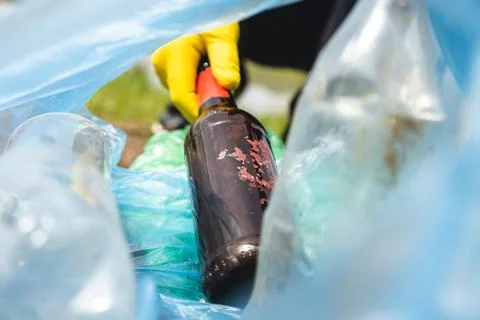 Close-up of a hand putting garbage in a plastic trash bag. Inside view Фото