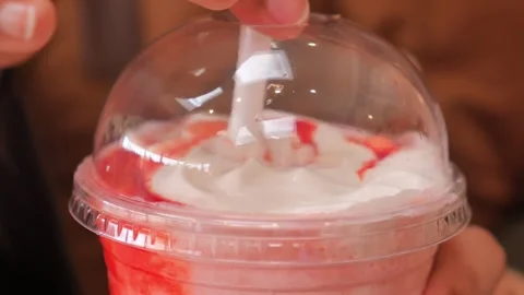 Close up of hand putting straw into dome lid of strawberry milkshake with w.. Stock Footage 332886477