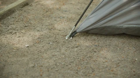 Close up of hand putting in tent peg in sand in slow motion on sunny day, 4k Stock Footage 111933032