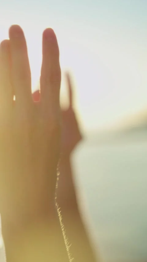 A close-up of a hand raised in a yoga or meditation pose, bathed in warm sunset Stock Footage 304684499