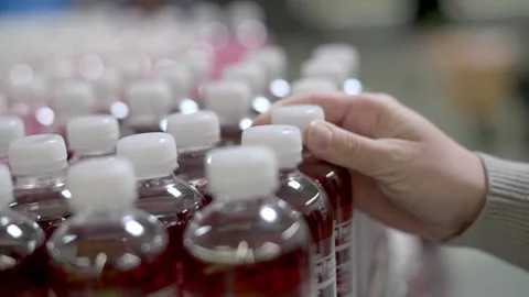 A close-up of a hand reaching for a bottle of red beverage from a shelf fille Vidéo 276398306
