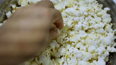 Close-up of a hand reaching into a bowl filled with crunchy popcorn. 스톡 동영상 323390642
