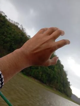 Close-up of a hand reaching out towards a cloudy sky during daytime Stock Photos