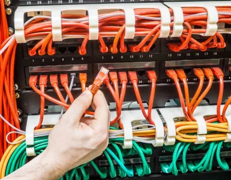 Close up of hand with red network cable and cables connected to switch Stock Photos