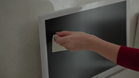 Close up of hand in red sleeve placing and adjusting sticky note with shape text Stock Footage 344404750