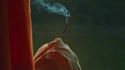 Close-up, the hand of a religious man in orange clothing holding a steaming Stock Footage 219722801