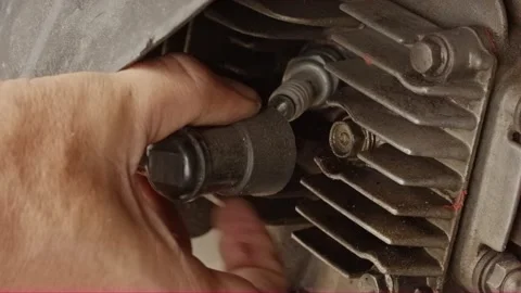 Close-up hand removing black spark plug cap from motorcycle engine fins Stock Footage 320127987