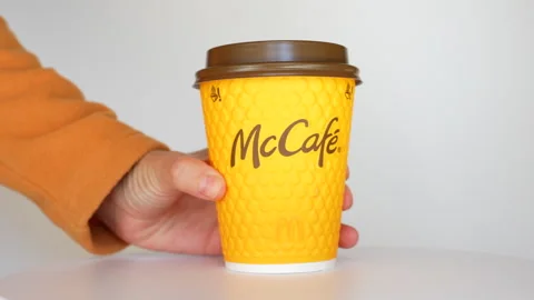 Close-Up of Hand Removing McCafe Orange Cup from Table Stock Footage 286823207