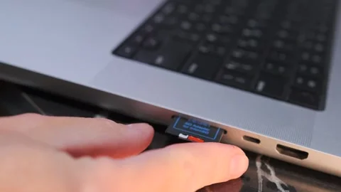 Close-up of a hand removing a memory card from a laptop port, showing data Stock Footage 333649413