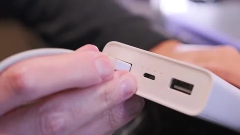 Close-up of a hand removing a USB cable from a power bank port, showing portable Stock Footage 333649404