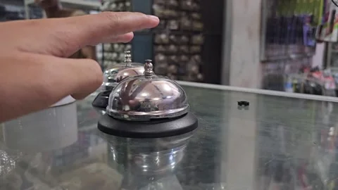 Close Up Hand Ringing Silver Service Bell On Glass Counter in Store Vídeos de archivo 332196171