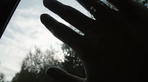 Close-up of hand with rings on the window of car on the go. Sun shining through Stock-Footage 67977701