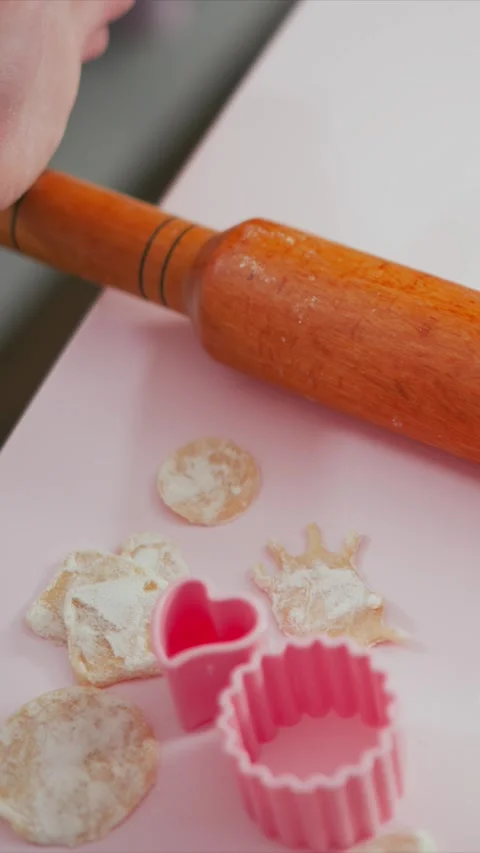 Close up of hand rolling carrot with cookie cutters on pink surface showing pin Stock Footage 345980329