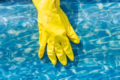 Close-up of a hand in a rubber glove while cleaning a garden pool. Preparation Stock Photos