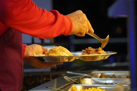 A close-up of a hand scooping curry onto a plate Stock-Fotos
