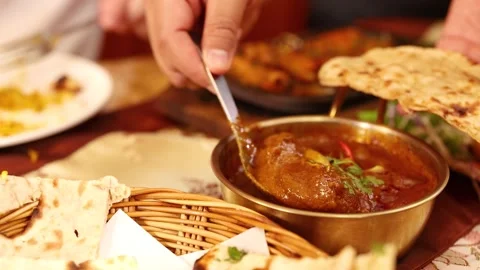 Close Up of Hand Scooping Indian Curry with Naan Bread Stock Footage 338424899