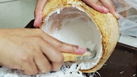 Close up of hand scraping fresh coconut meat with traditional scraper tool. Stock Footage 340506580