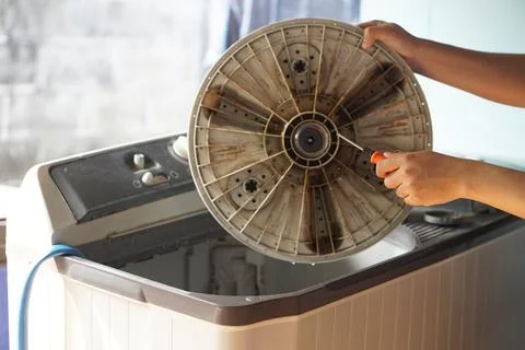 Close up hand screwdriver to remove out part of washing machine to fix and clean Stock Photos