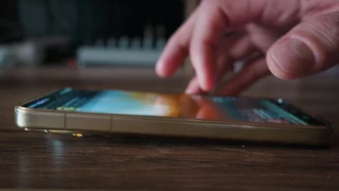Close Up of Hand Scrolling on Smartphone Screen Lying on Wooden Table 動画素材 339208551