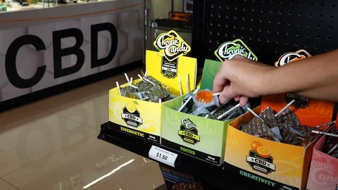 Close up of a hand selecting CBD infused lollypops in a retail store Stock Footage 120366006