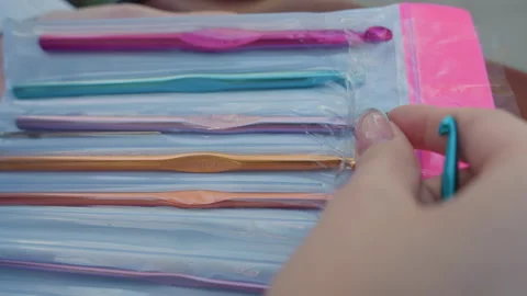 Close up of hand selecting colorful metal crochet hooks from plastic packaging Stock Footage 345128586