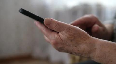 Close up of hand of senior lady using text message from smartphone sitting on Stock Photos