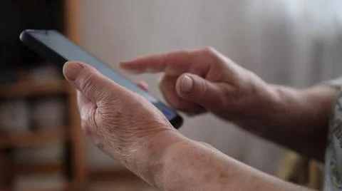 Close up of hand of senior lady using text message from smartphone sitting on Stock Photos