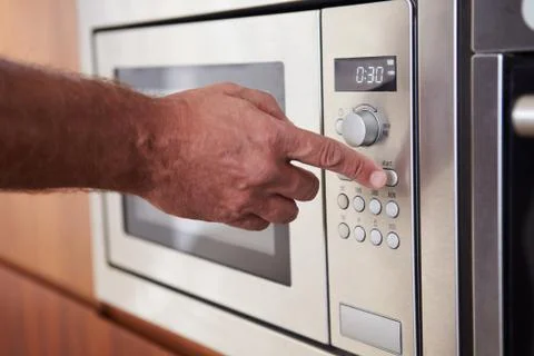 Close Up Of Hand Setting Timer On Microwave Oven Stock Photos