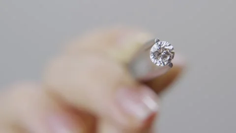 Close up - Hand shows a round shape diamond held by tweezers displayed to camera Stock Footage 154276784