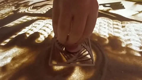 A close-up of a hand skillfully creating sand art, drawing intricate patterns wi Video stock 334735939
