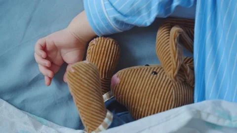 Close-up of the hand of a sleeping child next to a toy Stock Footage 131061704