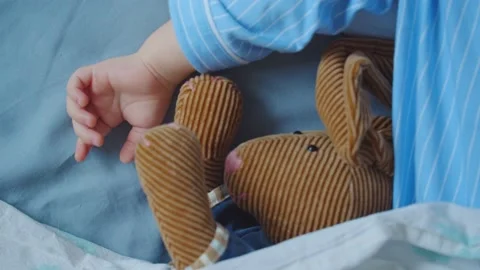 Close-up of the hand of a sleeping child next to a toy Video stock 131061788