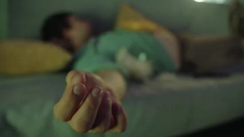 Close up of the hand of a sleeping man lying on a grey sofa in a living room Vidéo 314396736