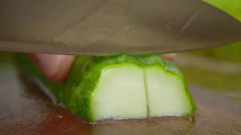 Close up of hand slicing fresh green cucumber with sharp knife on wooden board Stock Footage 340609434