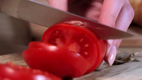 Close-up of hand slicing fresh red tomato with a sharp knife on wooden board Stock Footage 306095269