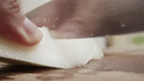 Close up of hand slicing white vegetable on wooden surface in kitchen with knife 库存影片 340406806