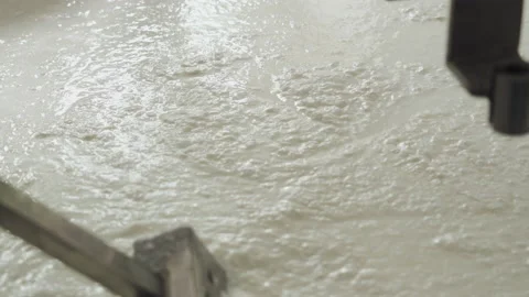 Close-up of a hand with a spatula for stirring cheese. Cheese making technology. 库存影片 177942901