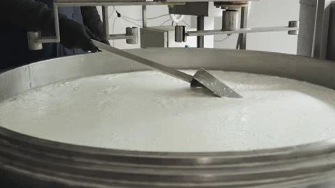 Close-up of a hand with a spatula for stirring cheese. Cheese making technology. Vidéo 177945218