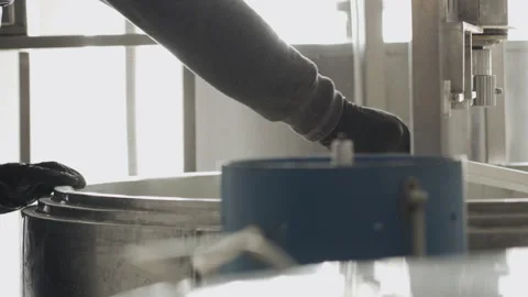 Close-up of a hand with a spatula for stirring cheese. Cheese making technology. Vidéo 177946684