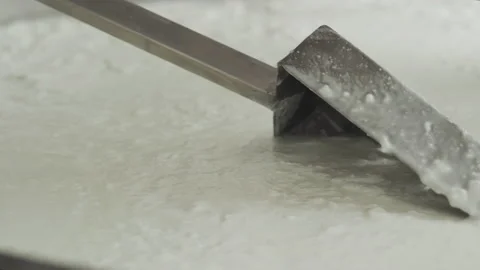 Close-up of a hand with a spatula for stirring cheese. Cheese making technology. Vidéo 177948950
