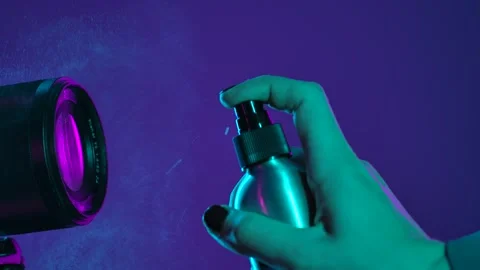 Close Up of Hand with Spray Bottle and Camera Lens under Neon Light Stock Footage 322169563