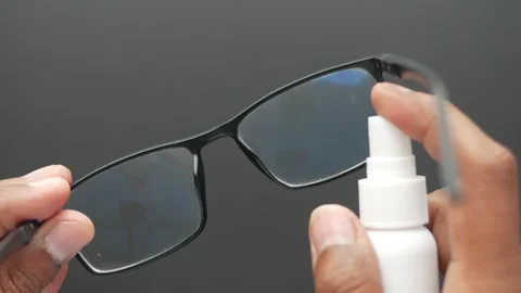 Close up of hand spraying lens cleaner on glasses for a clear view. Vídeos de archivo 333158692