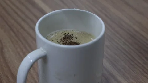 Close up hand sprinkling cocoa powder on a cappuccino sachet Stock Footage 310289434