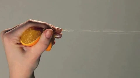 Close Up Hand Squeezing a Juicy Orange Fruit. Hand squeezing out fresh orange Stock Footage 265840976