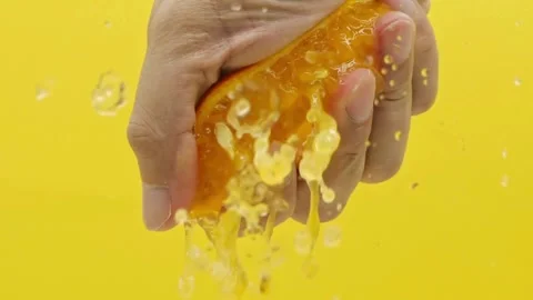 Close Up Hand Squeezing a Juicy Orange Fruit. Hand squeezing out fresh orange Stock Footage 265840989