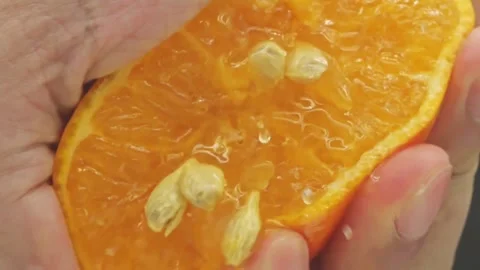 Close Up Hand Squeezing a Juicy Orange Fruit. Hand squeezing out fresh orange Stock Footage 265841268