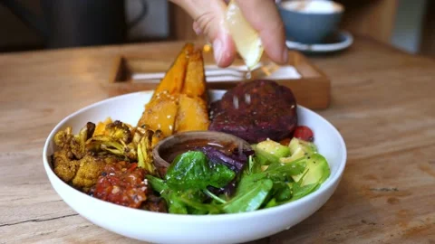 Close up of hand squeezing lemon juice on a healthy delicious vegan buddha bowl Video stock 154440859